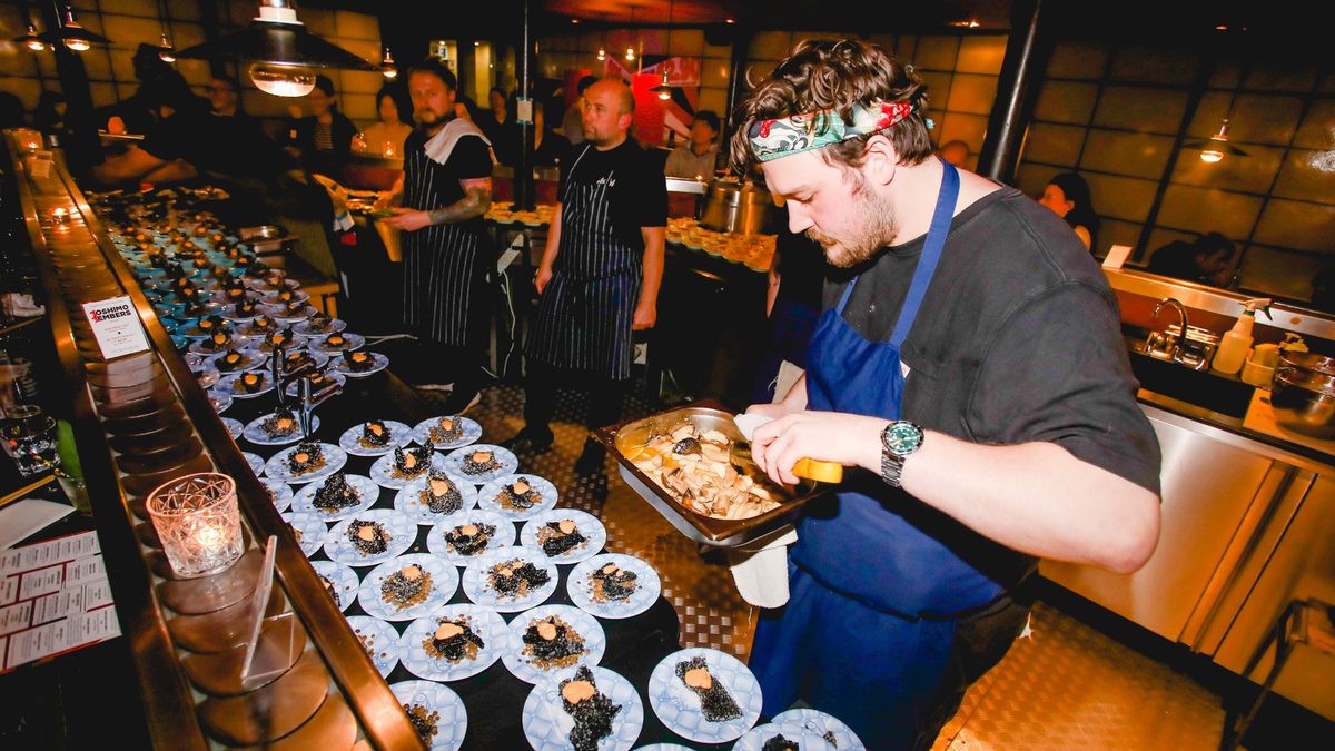 The belt loaded end to end with identical plates, the room watching them pass
